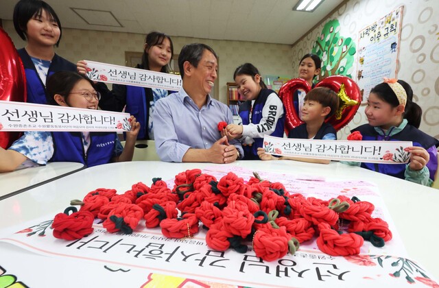 스승의 날을 하루 앞둔 14일 경기도 수원시 권선구 중촌초등학교 ‘수원애(愛)통통봉사단’ 학생들이 선생님에게 감사 메시지를 보이며 카네이션을 달아주고 있다. 학생들은 양말 제조 과정에서 나온 자투리 천 조각을 이용해