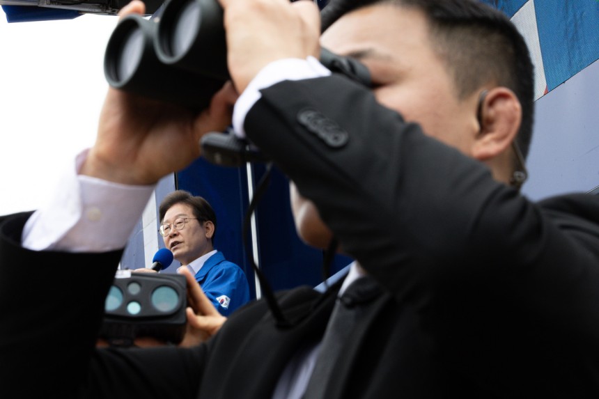 더불어민주당 이재명 대선후보가 16일 전북 군산시 구시청광장에서 열린 유세에서 지지를 호소하는 연설을 하는 가운데 경호원이 경계 근무를 서고 있다. 연합뉴스
