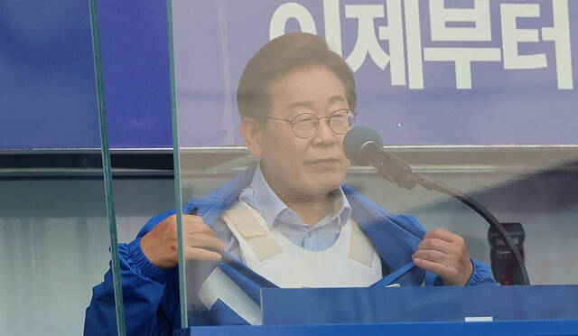 더불어민주당 이재명 대선 후보가 21일 자신의 지역구인 인천광역시 계양역 앞 유세에서 방탄유리, 방탄조끼 비판에 대해 항변하던 중 점퍼 속 방탄조끼를 보여주고 있다. 연합뉴스