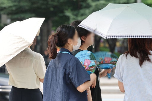 서울지역에 이틀째 폭염주의보가 지속중인 1일 서울 종로구 광화문광장 인근에서 시민들이 양산과 부채로 더위를 식히고 있다. 뉴시스