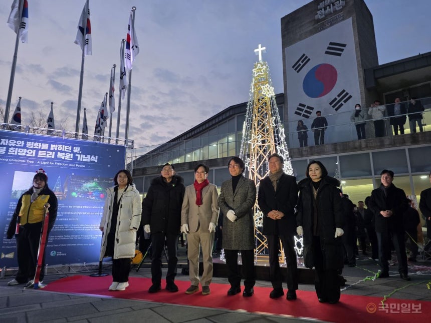 김병수 김포시장이 20일 김포시 애기봉평화생태공원 전시관 앞에서 11년 만에 부활한 '성탄 철탑 트리' 점등식을 진행하고 내빈과 기념촬영을 하고 있다.박재구 기자
