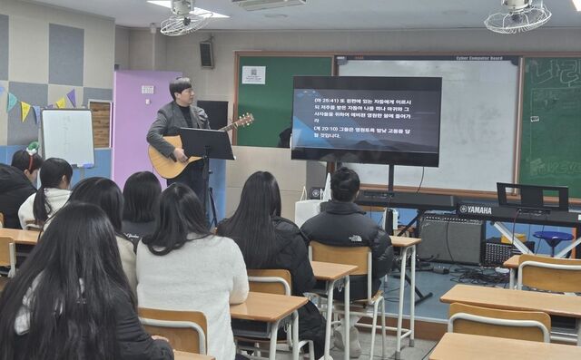 최새롬 학원복음화인큐베이팅 대표가 인천의 한 중학교 음악실에서 통기타를 메고 학생들과 함께 찬양을 부르고 있다.