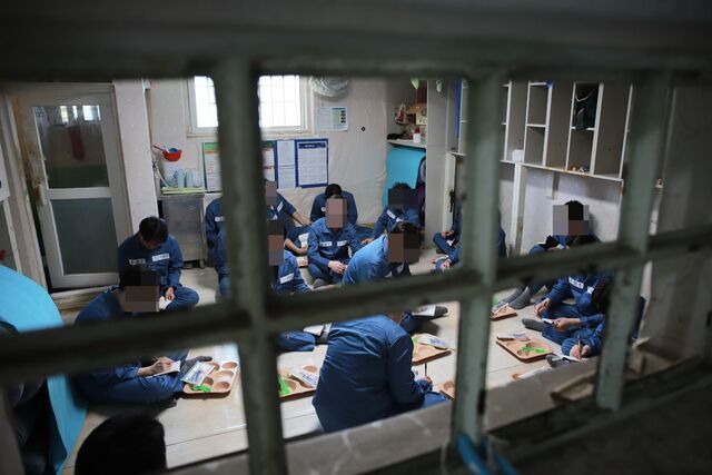 지난 15일 경기도 안양교도소에서 수용자 체험 중인 취재진이 수용자복을 입고 혼거실에 앉아 점심 식사를 기다리고 있다. 혼거실 정원은 9명이지만 수용 공간이 부족해 평소 15~17명이 수용된다. 법무부 제공