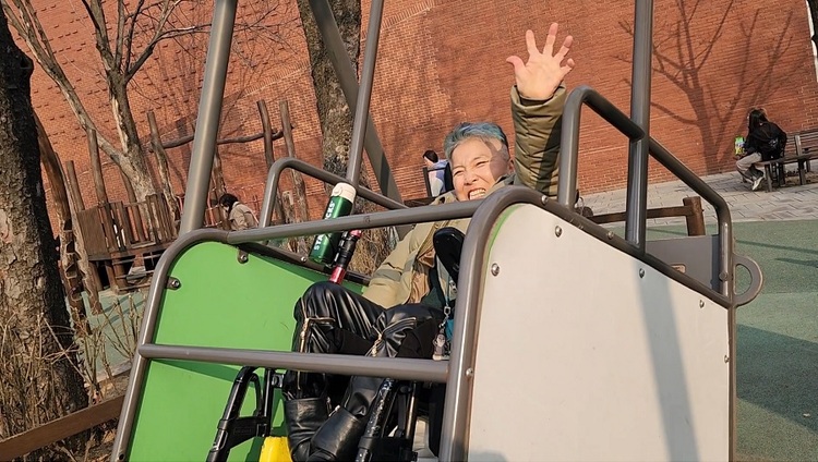 서울 혜화역 지하철 선전전을 하고 돌아가는 길. Moon이 마로니에 공원의 휠체어 그네를 타고 있다. 집에만 있다가 25살에 사회에 나온 Moon은 아직 그네 타는 걸 좋아한다. “물리적 나이는 50대지만, 사회적 