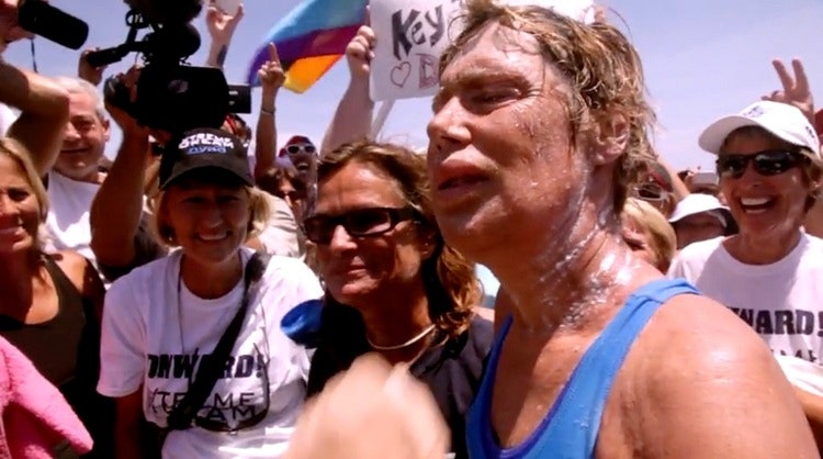 플로리다 해변에 발을 딛는 순간의 다이애나 나이애드의 모습. 그 뒤로 작게 프라이드 깃발이 보인다. 〈파도를 헤치고〉 예고편 중. (출처: Netflix)    