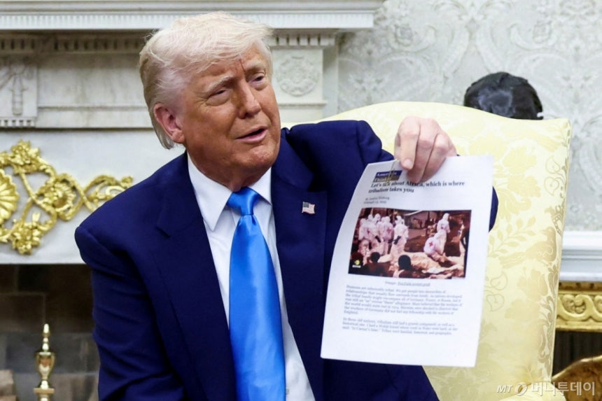 (워싱턴DC 로이터=뉴스1) 류정민 특파원 = 도널드 트럼프 미국 대통령이 21일(현지시간) 미국 워싱턴DC 백악관 집무실에서 사망한 남아프리카공화국 백인에 관한 기사 출력물을 들어 보이고 있다. 2025.05.21