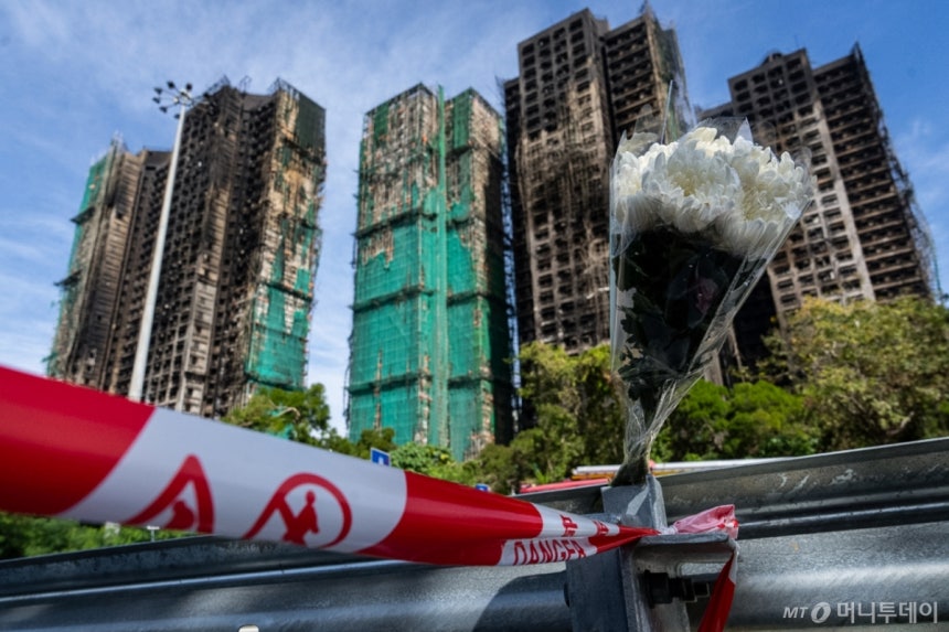 28일(현지 시간) 홍콩 타이포 지구 '웡 푹 코트' 아파트 단지 화재 현장 인근에 희생자들을 애도하는 국화가 꽂혀 있다. 화재 진화가 종료된 가운데 사망자 수는 128명으로 늘어
