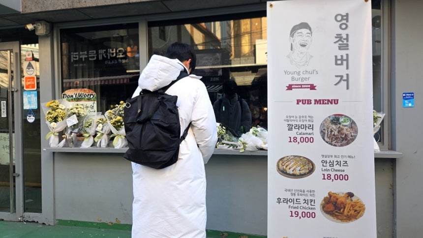 15일 오전 고려대 기계공학부 학생 홍모씨(20)가 영철버거 가게 앞에서 고개를 숙이고 추모하는 모습./사진=김서현 기자.