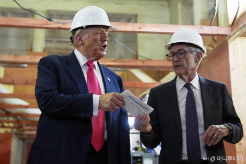 [워싱턴=AP/뉴시스] 도널드 트럼프(왼쪽) 미국 대통령이 24일(현지 시간) 워싱턴DC 연방준비제도(연준) 건물 개보수 현장을 방문해 제롬 파월 의장에게 비용 관련 문서를 건네고 있다.트럼프 대통령은 파월 의장 