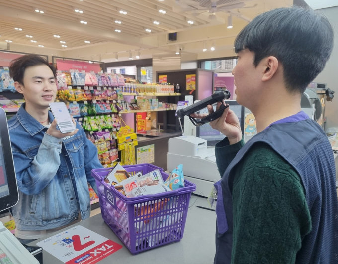 CU에서 외국인 관광객이 AI 통역 서비스를 이용하는 모습./사진제공=BGF리테일