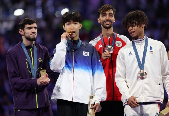 박태준(왼쪽 둘째)이 8일 프랑스 파리 그랑팔레 태권도경기장에서 열린 2024 파리올림픽 태권도 남자 58kg급 시상식에서 메달을 받은 뒤 입에 물어보고 있다. 연합뉴스