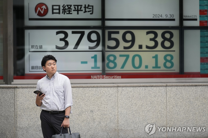  30일 일본 증시 대표 주가지수인 닛케이지수가 폭락한 가운데 한 남성이 증시 현황판 앞에 서 있다. [AP=연합뉴스]