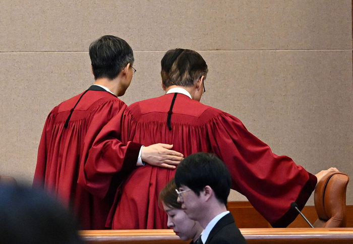  헌법재판소 대심판정에서 윤석열 대통령에 대해 파면 결정을 선고한 뒤 김형두 헌법재판관의 어깨를 두드리며 문형배 헌법재판소장 권한대행(왼쪽)이 퇴장하고 있다.[사진 출처 = 사진공동취재단]