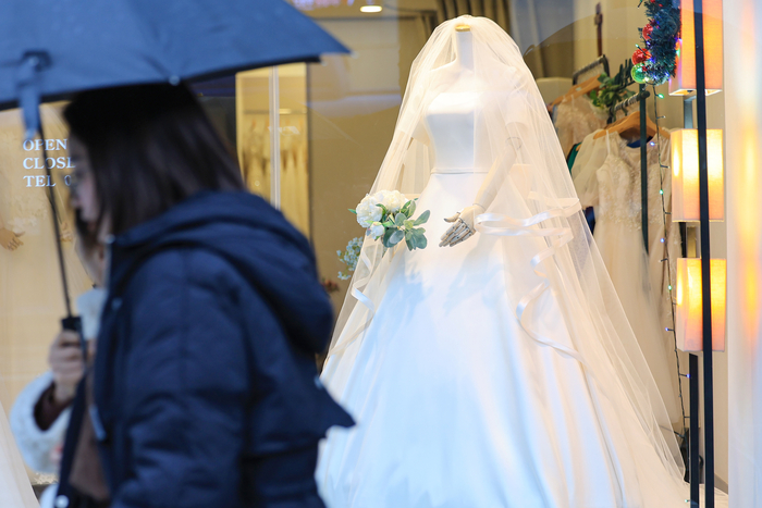  서울 마포구 아현동 웨딩거리 한 웨딩드레스 판매점 앞을 시민들이 지나가고 있다.[사진 = 연합뉴스]