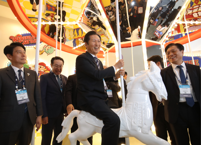 정청래 더불어민주당 당대표가 14일 부산 해운대구 벡스코에서 열린 ‘지스타 2025’를 찾아 웹젠이 마련한 포토존에서 회전목마를 타고 있다. [뉴스1]