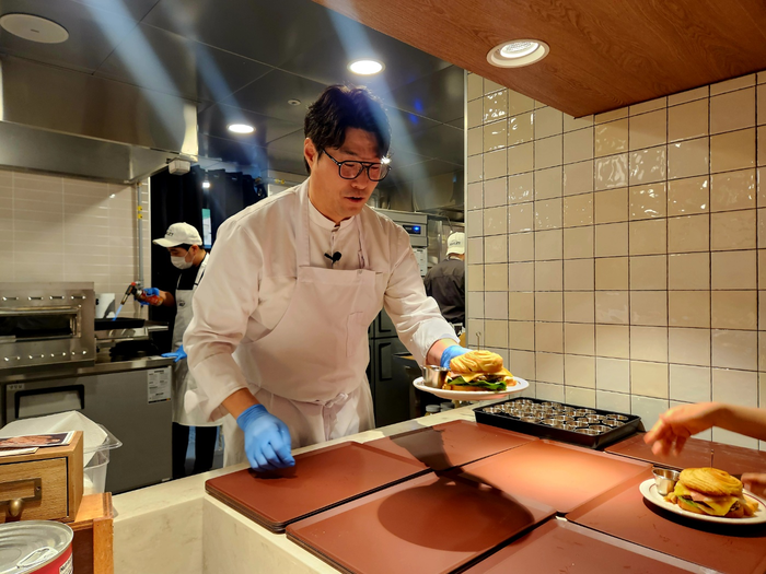  19일‘하우스 오브 애슐리’에서 애슐리퀸즈와 협업한 오세득 셰프가 직접 만든‘한우 비프웰링턴 버거’를 나눠주고 있다.<박윤예 기자>