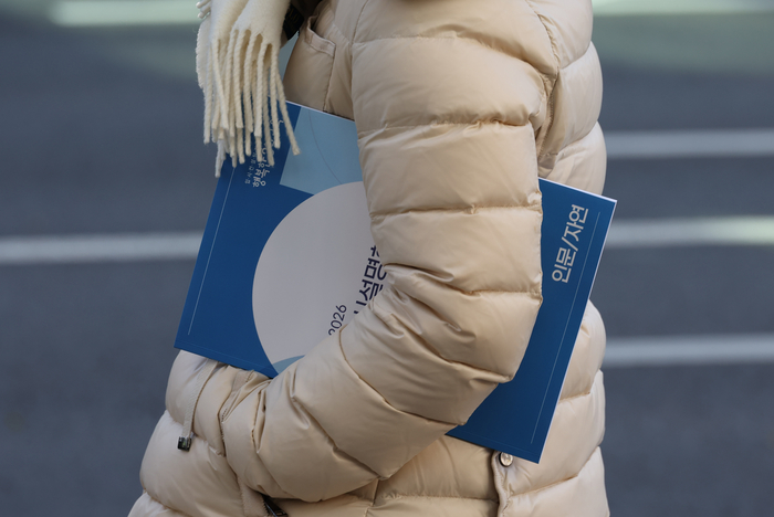  지난 4일 서울 대치동 학원가에서 한 시민이 2026학년도 입시설명회 자료를 들고 있는 모습.[연합뉴스]