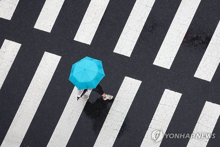  서울 세종대로 인근에서 우산을 쓴 시민이 길을 건너고 있다.[연합뉴스]