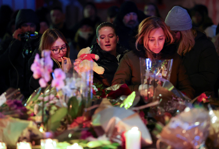  스위스 클럽 화재로 숨진 희생자들을 추모하기 위해 꽃다발을 놓는 시민들.[로이터 연합뉴스]
