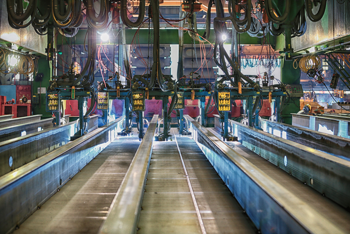  경남 거제시 한화오션 옥포조선소 선체 조립 공장에서 용접 로봇이 병렬로 연결된 채 숙련공의 속도로 작업하고 있다.[한화오션]