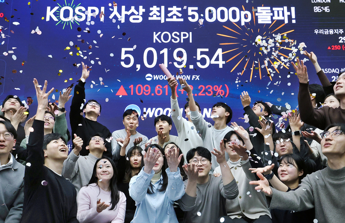  (서울=뉴스1) 오대일 기자 = 한국 증시가 사상 처음으로‘코스피 5000’쾌거를 달성한 22일 서울 중구 우리은행 본점 딜링룸에서 직원들이 장중 최고가가 찍힌 전광판을 배경으로 코스피 5000 돌파를 축하하고