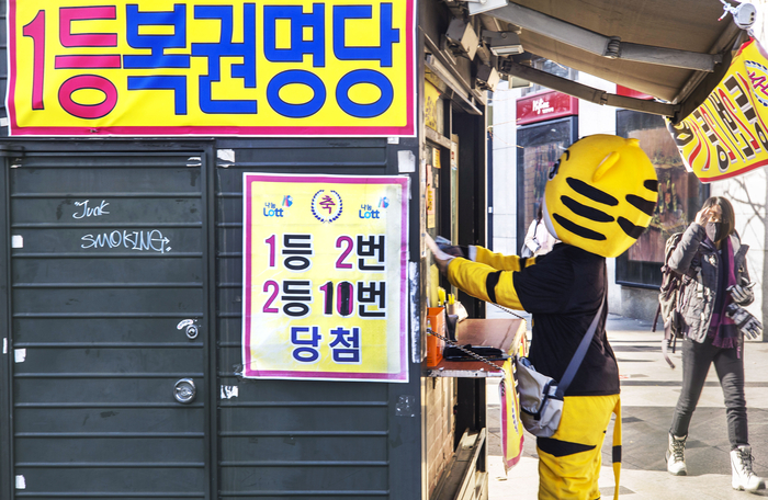 인형 탈을 쓴 아르바이트생이 로또 복원을 구매하고있다. [이충우 기자]