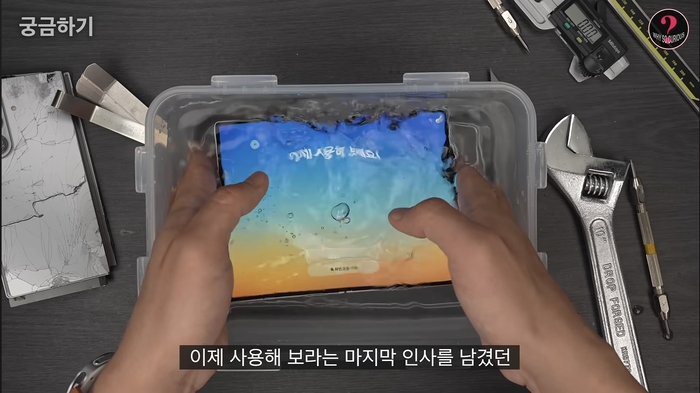 언박싱 유튜버 ‘궁금하기’가 최근 공개한 갤럭시 Z 폴드8 실험 영상. 후면 카메라 렌즈 유리를 제거한 스마트폰을 물 속에 넣는 모습. [유튜브 캡처]