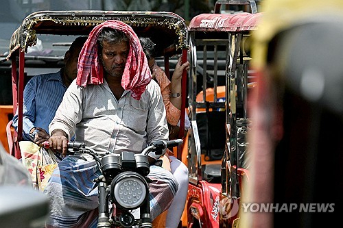 2024년 5월 3일(현지시간) 인도 뉴델리에서 지속되는 폭염에 한 릭샤 운전사가 수건으로 머리를 감싼 채 운전하고 있다. AFP 연합뉴스