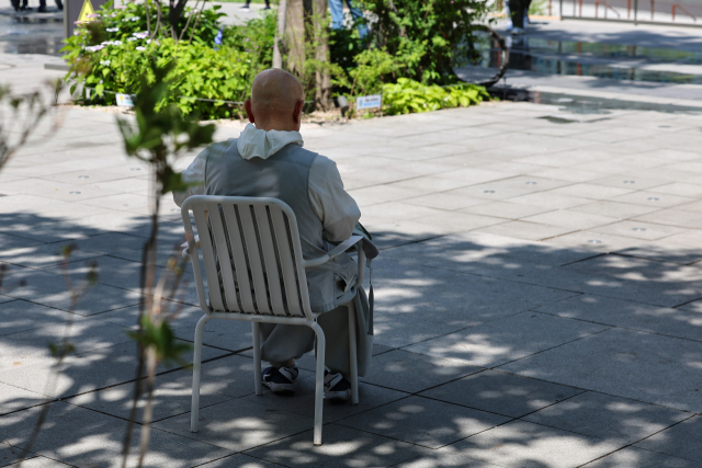 지난 3일 서울 종로구 광화문광장에서 한 시민이 나무 그늘 아래에 앉아 쉬고 있다. 연합뉴스