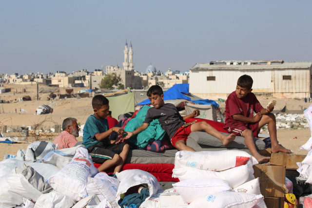 이스라엘군의 공격을 피해 안전한 곳으로 피란하려는 팔레스타인 어린이들이 12일(현지시간) 가자지구 최남단 도시 라파에서 소지품과 함께 차 위에 올라탄 채 납작하게 구운 빵을 먹고 있다. AP=연합뉴스
