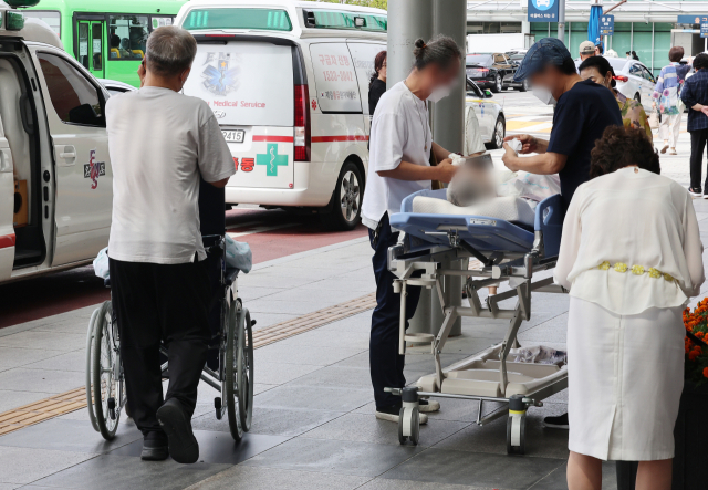 정부의 의대 정원 증원에 의료계가 반발하며 의정 갈등이 장기화하고 있는 25일 서울의 한 대형 병원 앞에서 환자가 침상에 누운 채 대기하고 있다. 연합뉴스