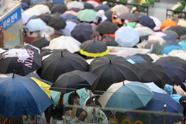 지난 4일 서울 잠실야구장을 찾은 관람객들이 갑자기 소나기가 내리자 우산을 펴고 있다. 연합뉴스