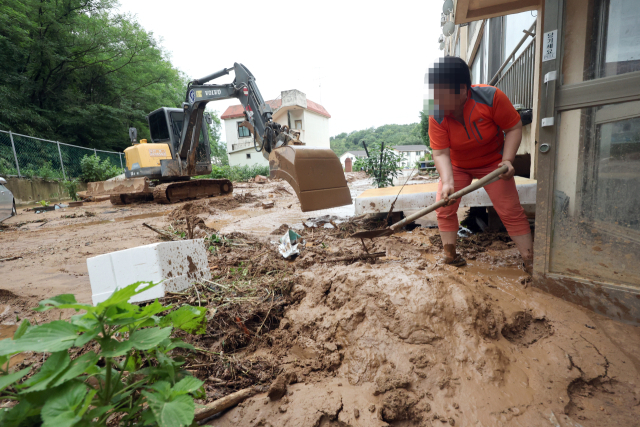 한 주민이 10일 폭우로 산사태가 나면서 전북 군산시 성산면 한 아파트로 내려온 토사를 걷어내고 있다. 연합뉴스