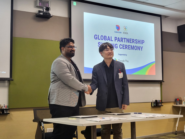 In the photo provided by Yang Ji-hye, Laris Goodieparty, co-founder and COO of DashToon (left), and Seo Beom-gang, president of the Korea Webtoon Industry Association, shake hands at the global partnership signing ceremony. By Yang Ji-hye