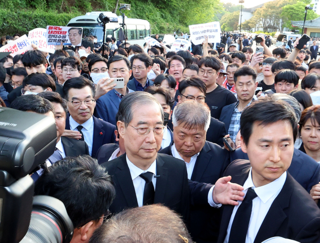 2일 오후 광주 북구 국립5·18민주묘지를 찾은 한덕수 전 총리가 광주비상행동 등 시민사회단체 관계자들에게 가로막히자 발길을 돌리고 있다.연합뉴스