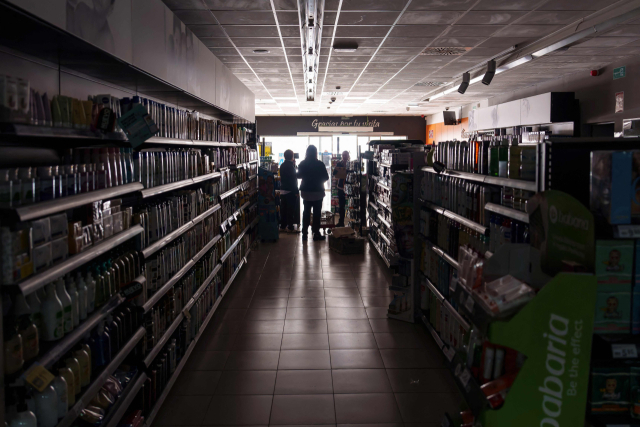 TOPSHOT - Employees stand inside a supermarket without lights in Burgos on April 28,2025,during a massive power cut af