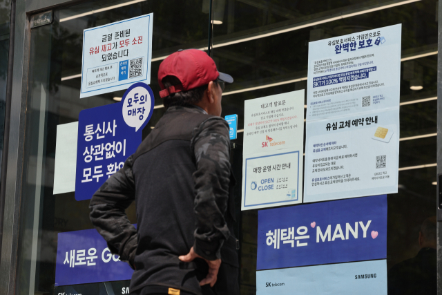 지난 2일 서울 시내의 한 SK텔레콤 대리점 앞에서 한 소비자가 유심 재고 소진 및 유심보호서비스 관련 안내문을 살펴보고 있다.연합뉴스