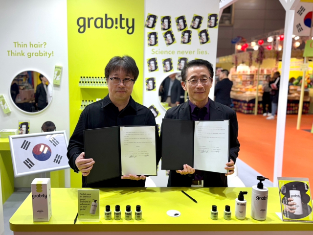 김재겸 롯데홈쇼핑 대표(오른쪽)와 이해신 폴리페놀팩토리 대표가 그래비티 수출 독점 계약을 체결한 뒤 기념 촬영을 하고 있다. 사진 제공=롯데홈쇼핑