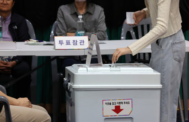 제21대 대통령선거 투표일인 3일 오후 울산 남구 월평초등학교 체육관에 설치된 신정4동 제2투표소에서 투표참관인들이 지켜보는 가운데 한 유권자가 기표를 마친 투표지를 투표함에 넣고 있다. 연합뉴스