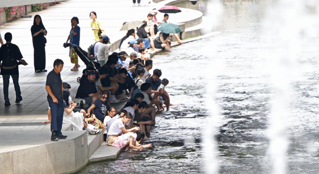 폭염이 이어진 6일 서울 청계천에서 시민들이 물에 발을 담그거나 그늘에서 휴식을 취하는 등 더위를 피하고 있다. 성형주 기자