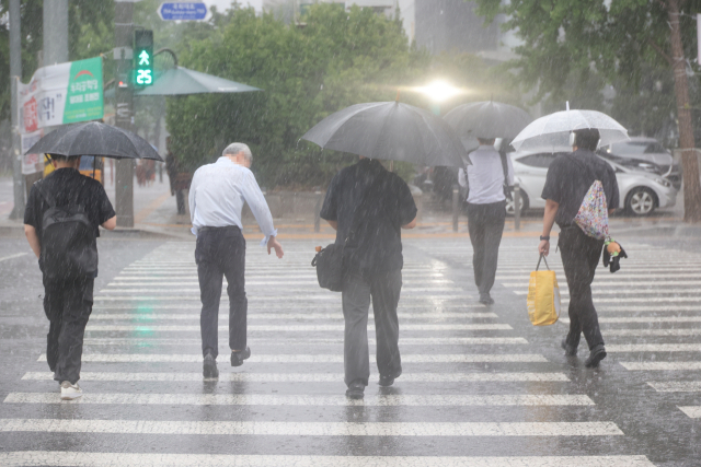 서울 서남권에 호우주의보가 발효된 8일 서울 영등포구 여의도 국회 인근에서 시민들이 우산을 쓰고 이동하고 있다. 연합뉴스