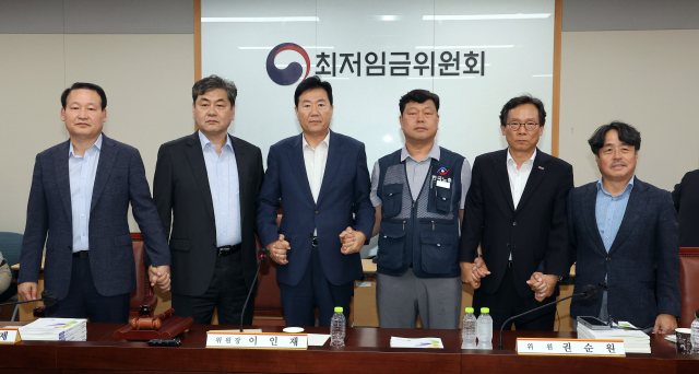 10일 정부세종청사에서 열린 제12차 전원회의에서 내년 최저임금을 시간당 1만320원으로 17년만에 합의로 결정한 공익위원-사용자위원-근로자위원들이 손을 잡고 기념촬영을 하고 있다. 왼쪽부터 하헌제 상임위원, 이인재