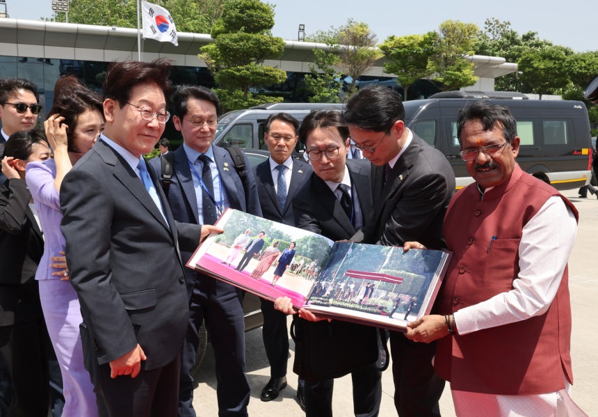 인도 국빈방문을 마치고 베트남으로 향하는 이재명 대통령이 21일(현지시간) 뉴델리 팔람 공군기지에서 인도측 인사로부터 사진첩 선물을 받고 있다. 연합뉴스