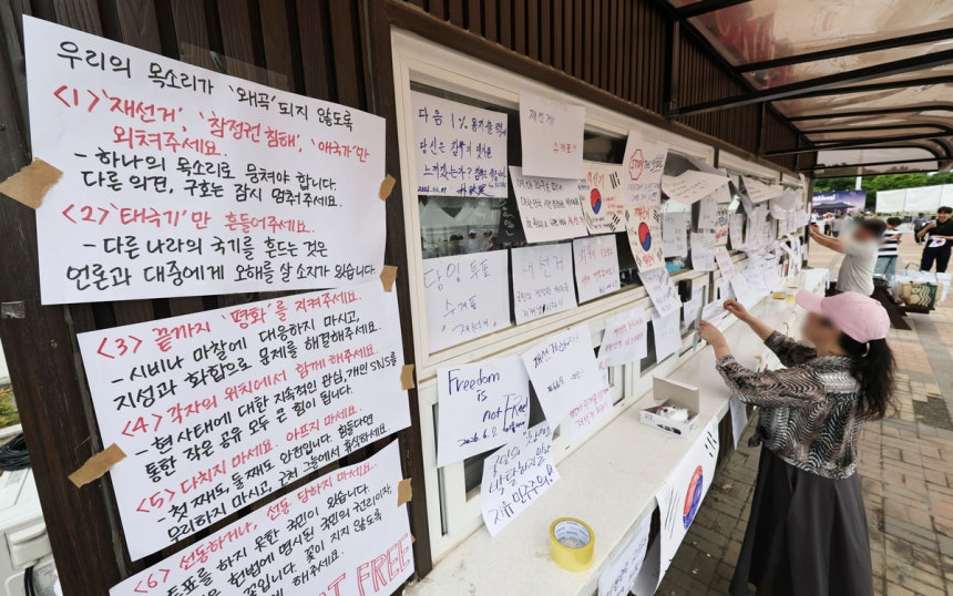 6·3 지방선거 투표지 부족 사태를 규탄하며 재선거를 요구하는 ‘잠실 개표소 봉쇄 시위’가 계속되고 있는 7일 서울 송파구 올림픽공원 핸드볼경기장 앞 매표소 부스에 재선거를 요구하는 문구 등이 적힌 종이가 붙어있다.