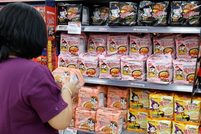 A tourist choosing spicy chicken stir-fried noodles at a large mart in downtown Seoul. News1