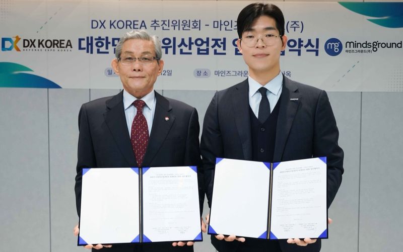 마인즈그라운드(주) 민환기 대표(사진 오른쪽)와 DX KOREA 2026 김영후 추진위원장이 대한민국 방위산업전(DX KOREA) 2026 업무협약서를 12일 체결했다.