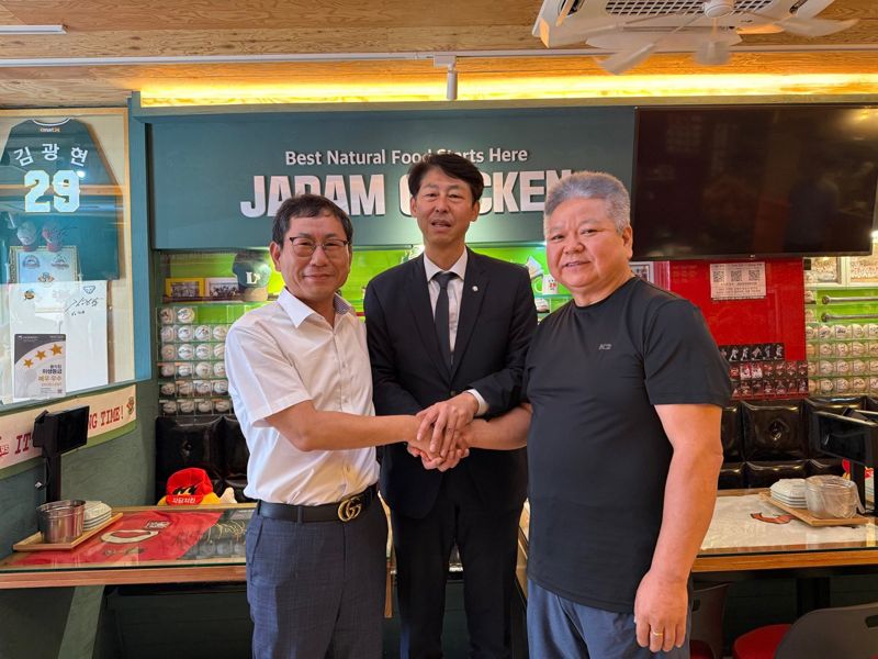 매장 앞 전광판에 정치적 메시지를 담았다는 이유로 폐업할 뻔한 치킨가맹점이 기사회생했다. 사진은 25일 해당 매장을 찾은 나명석 자담치킨 회장이 공식 사과 후 더불어민주당 이훈기 의원, 가맹점주인 황선인씨와 손을 맞