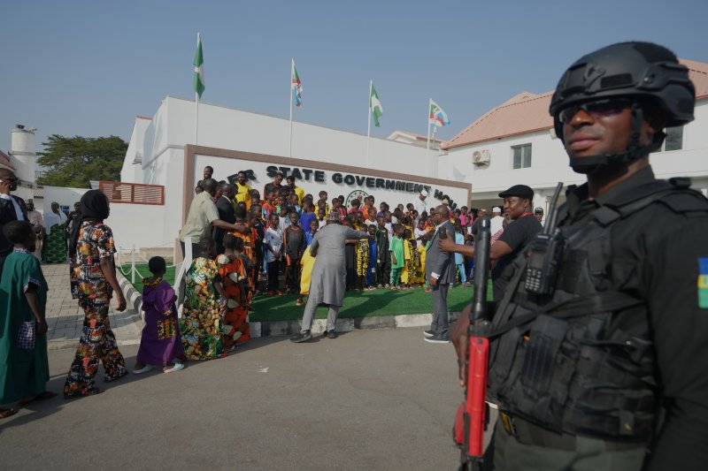 지난 22일(현지시간) 나이지리아 니제르주(州) 민나에서 풀려난 가톨릭 기숙학교 학생과 선생들이 정부 청사에 도착한 가운데 현지 경찰이 주변을 경계하고 있다.지난 11월 21일 니제루 파피리의 세인트 메리 학교에서