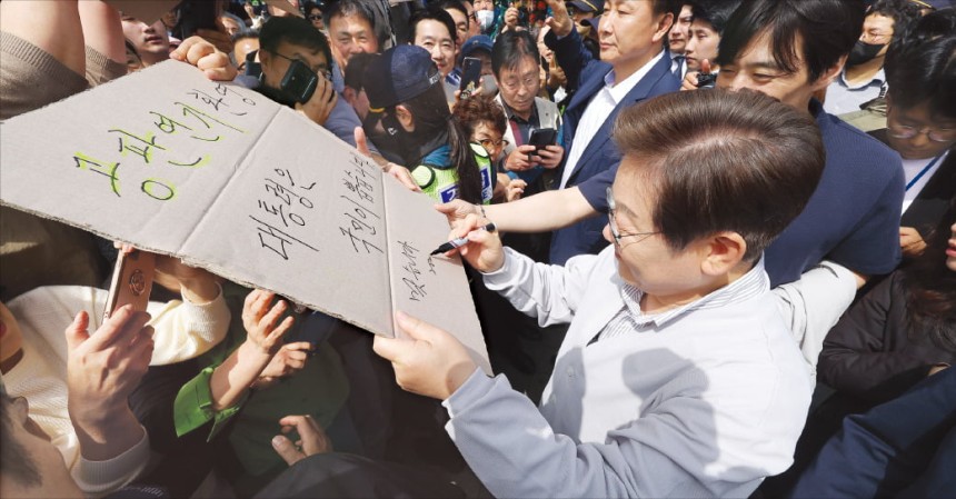 < 사인하는 李 > 이재명 더불어민주당 대선 후보가 7일 전북 전주시 풍남문 앞 광장에서 한 지지자가 든 공판 연기 축하 팻말에 사인하고 있다.연합뉴스
