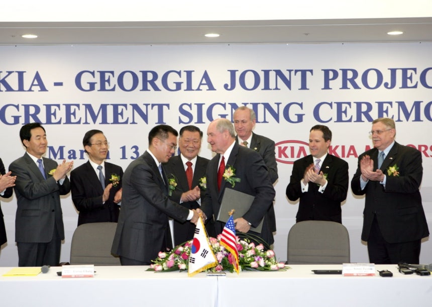 2006년 기아 조지아 공장 투자 계약식에서 정몽구 명예회장이 지켜보는 가운데 정의선 회장과 소니 퍼듀 조지아 주지사가 투자 계약서에 서명한 후 악수하고 있다. 사진=현대차그룹